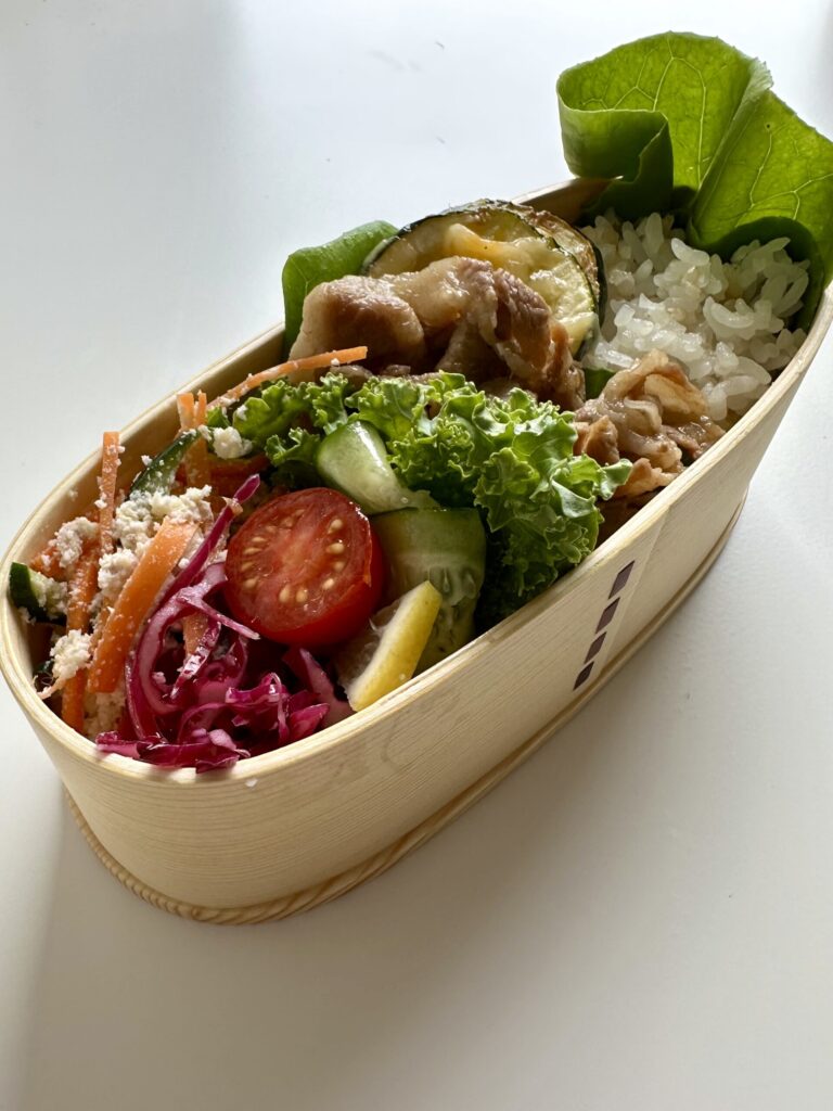 お弁当を横から撮影。生姜焼き、ズッキーニのチーズ焼き、紫キャベツ、おからサラダが見やすく並ぶ腸活お弁当