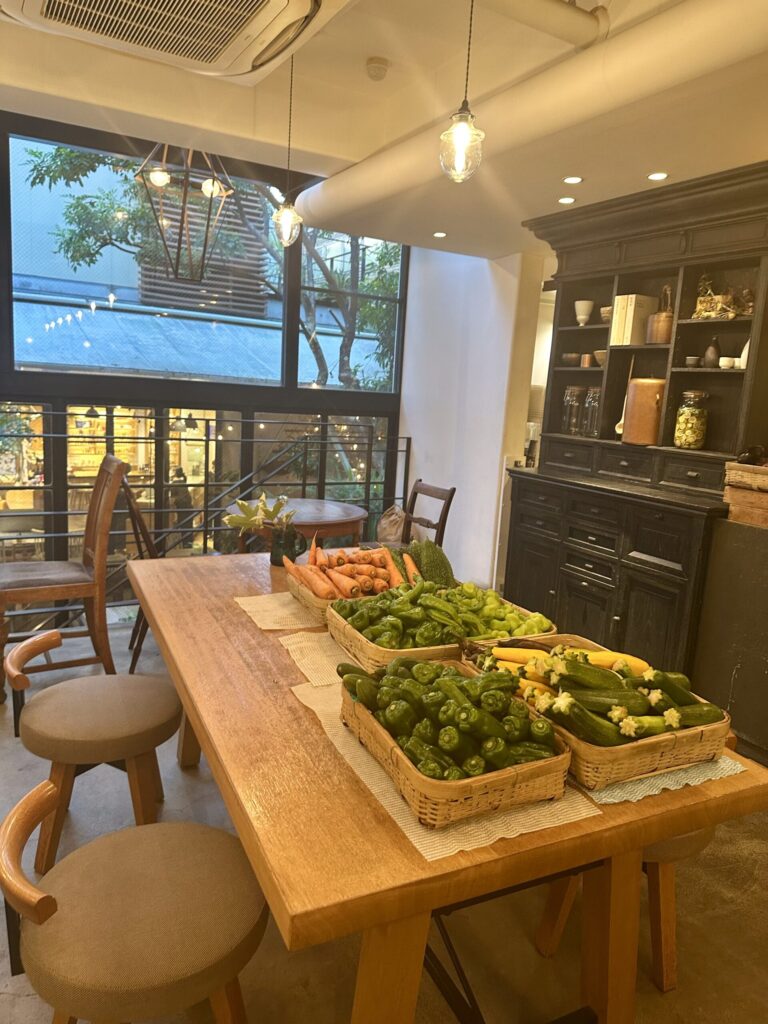 カフェで使用される新鮮なオーガニック野菜が並ぶ店内の様子。自然素材にこだわった雰囲気。